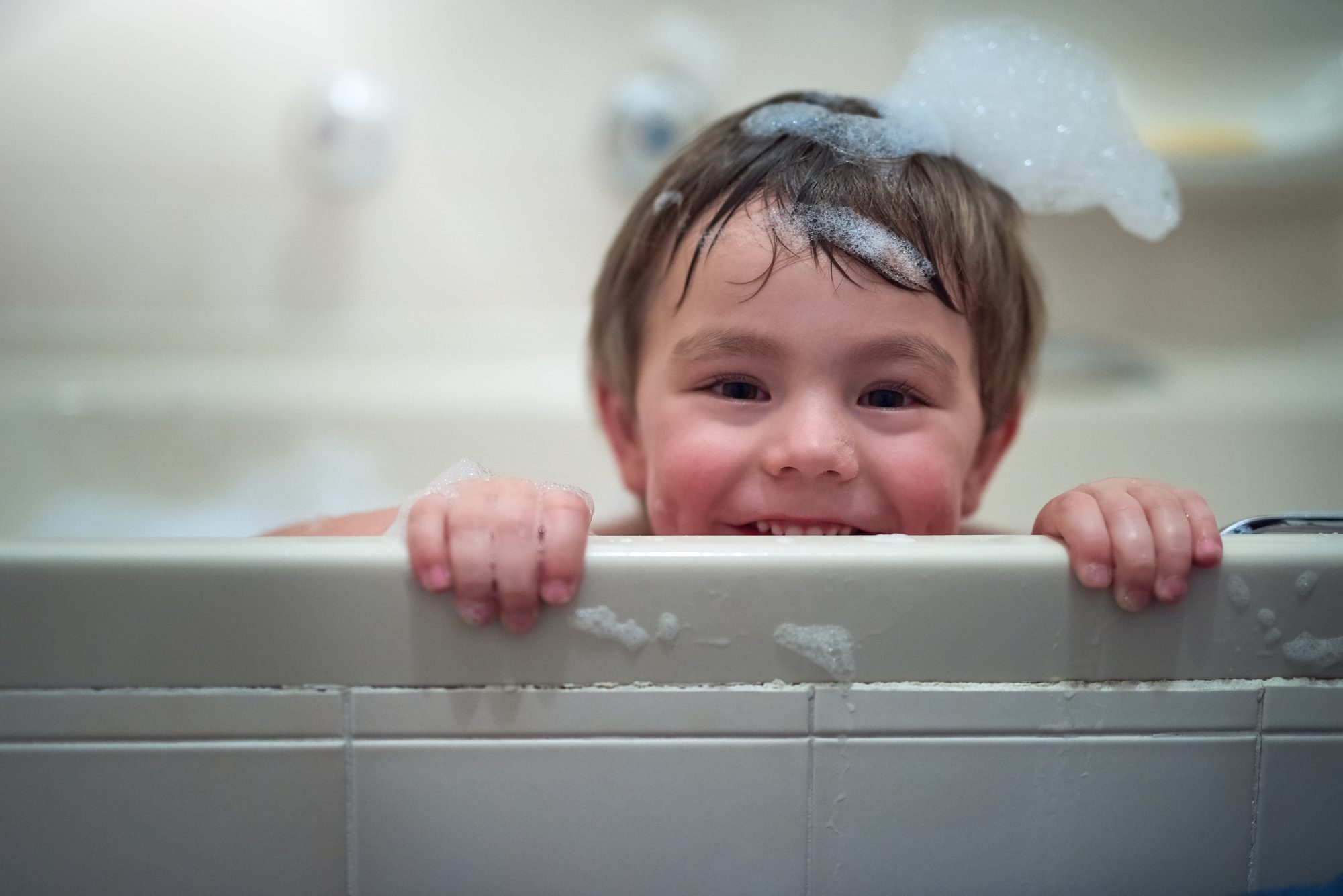 portrait of a little boy smiling and sitting in a bath tub