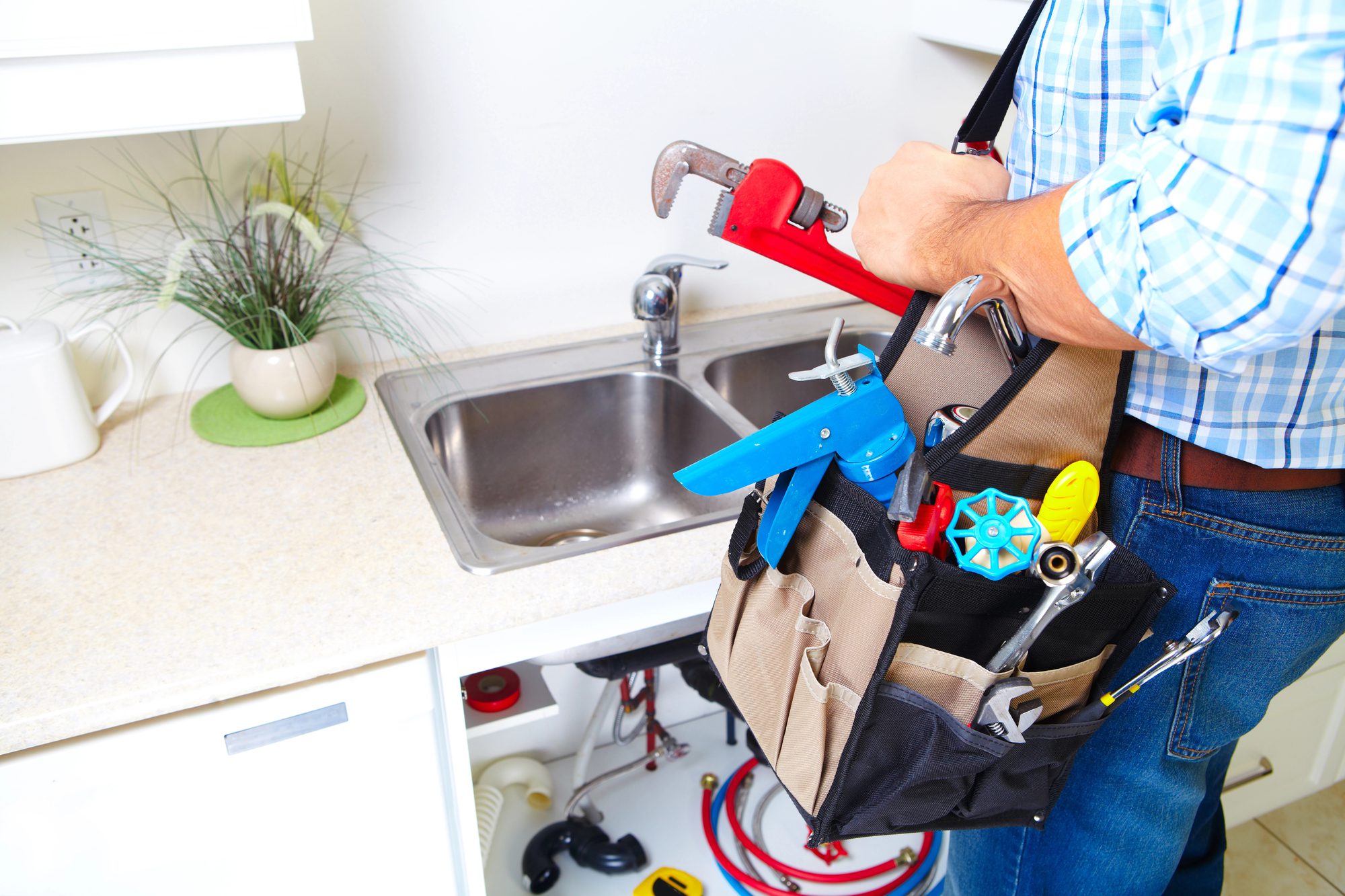 a plumber at work with an array of plumbing tools